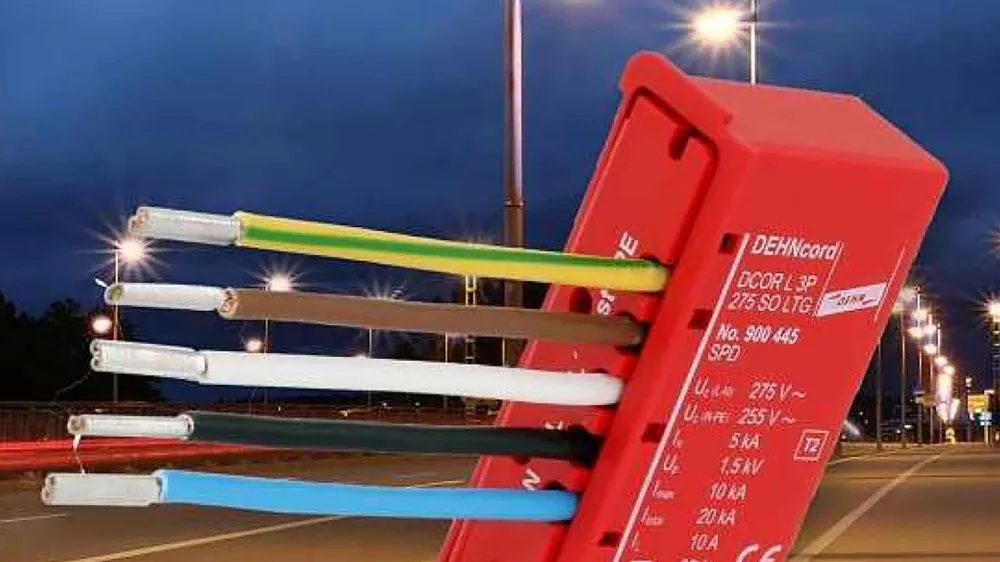 Red surge protection device with multiple colored wires connected, shown against a nighttime street with illuminated streetlights.