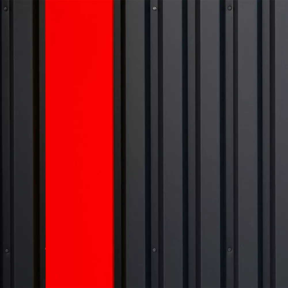 Close-up of a dark metal wall with a single bright red vertical panel.
