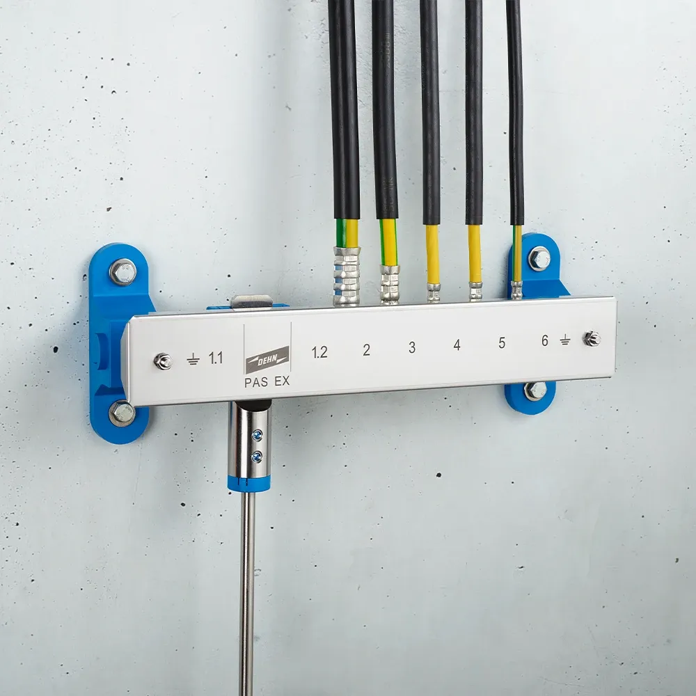 Wall-mounted grounding bar with multiple connected cables and labeled terminals, marked "PAS EX" on a metal rail.