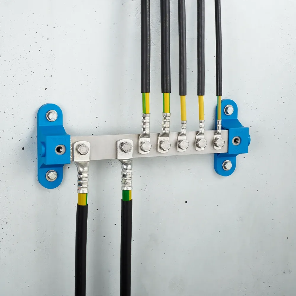 Wall-mounted grounding bar with metal terminals and connected black and yellow-green cables on a light gray wall.