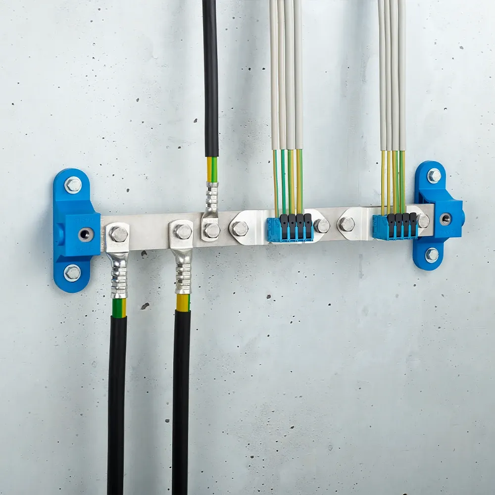 Wall-mounted grounding bar with metal terminals, connected black and yellow-green cables, and blue mounting brackets on a light gray wall.