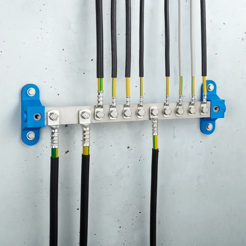 Wall-mounted grounding bar with metal terminals, connected black and yellow-green cables, and blue mounting brackets on a light gray wall.