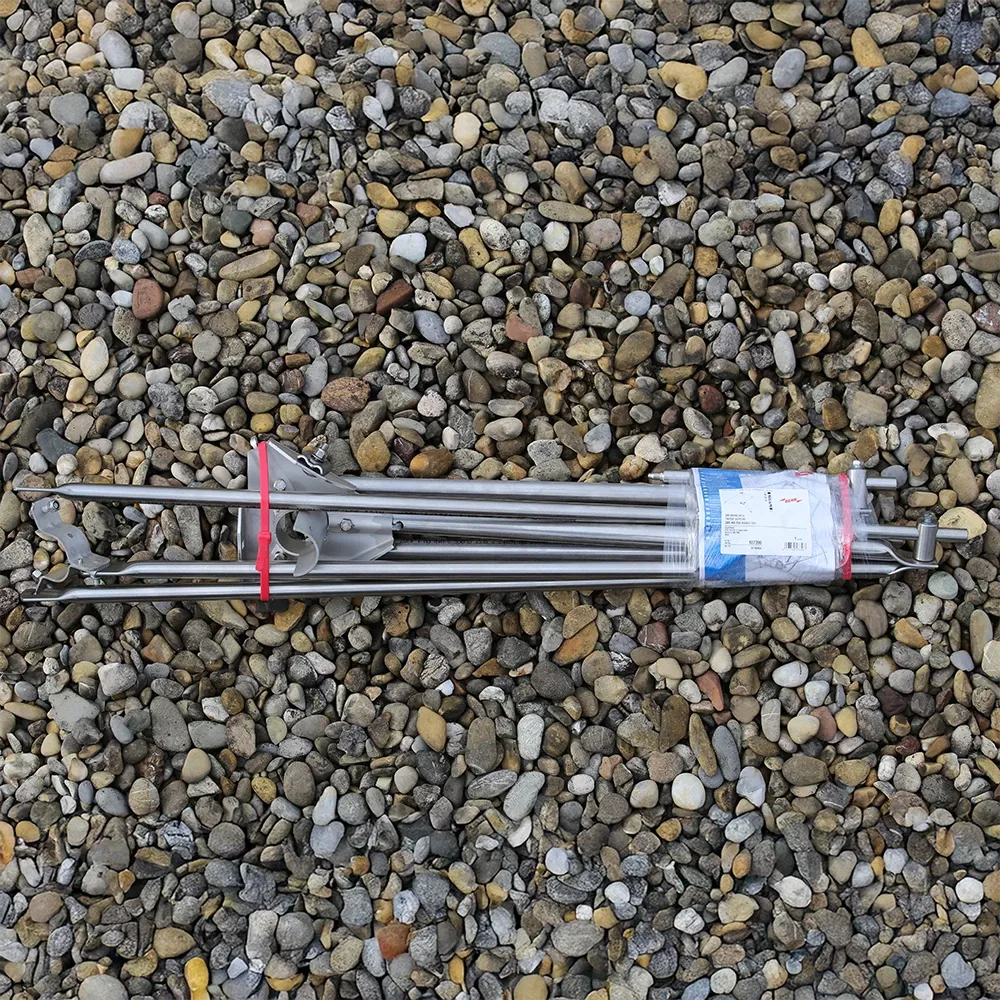 Bundled metal rods with clamps and straps, wrapped with a label, lying horizontally on a gravel surface.