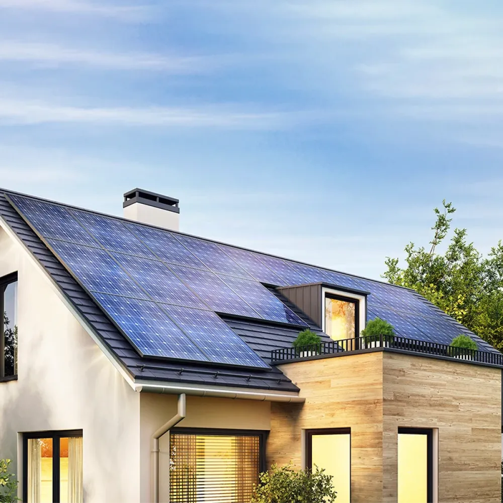 Modern single-family house with rooftop solar panels, large windows, and surrounding trees under a clear blue sky.