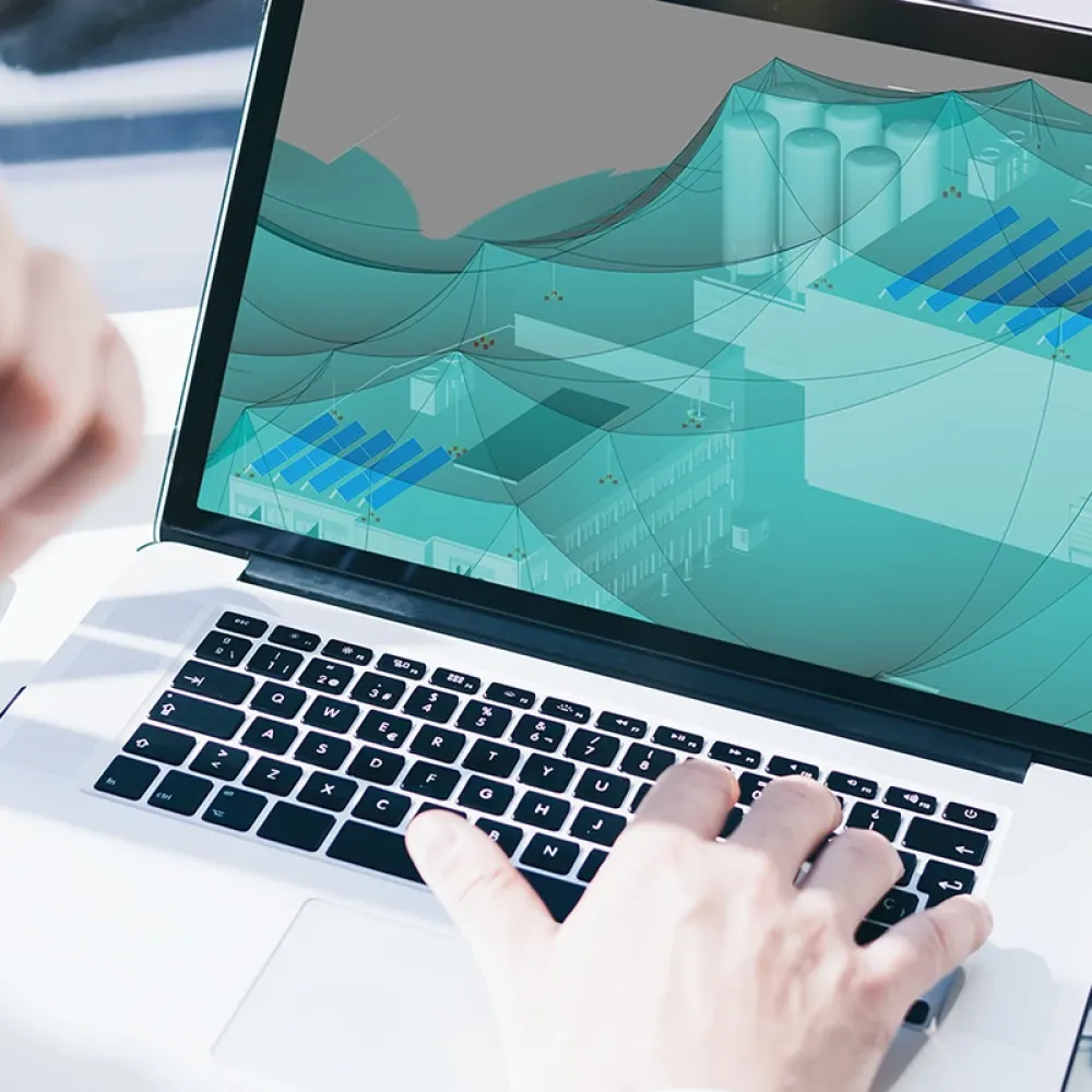 Laptop screen showing electrical planning software with a 3D protection zone model while a person works at the keyboard.