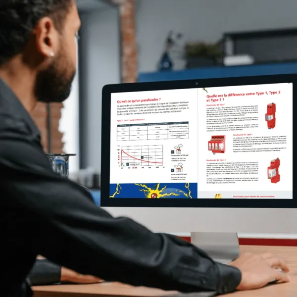 Man viewing guide about surge protection devices on computer screen showing Type 1, Type 2 and Type 3 explanations.
