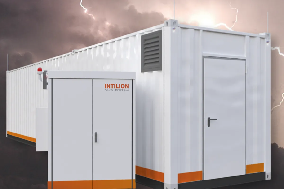Modular, white, containerized power unit with orange accents, alongside a smaller control panel, against a backdrop of stormy weather with lightning.