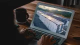 Laptop screen displays a row of battery storage units next to solar panels in a landscape.